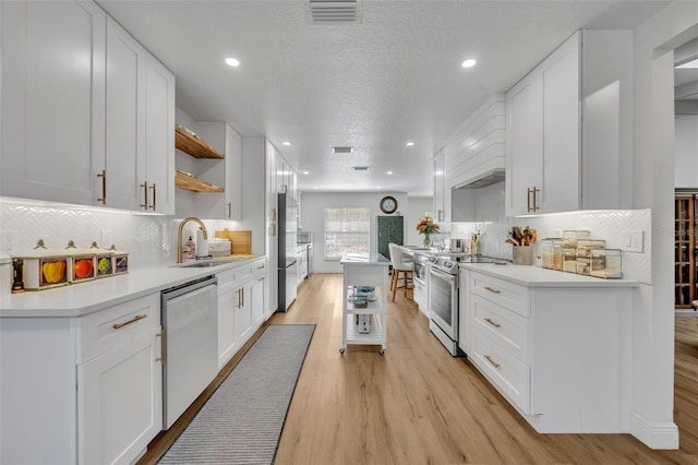 kitchen featuring sink, stainless steel appliances, light hardwood / wood-style flooring, a textured ceiling, and white cabinets