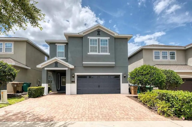traditional-style home featuring decorative driveway, stucco siding, and an attached garage
