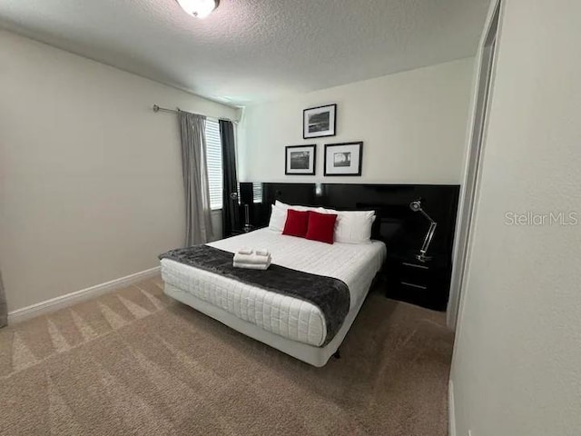 carpeted bedroom featuring baseboards and a textured ceiling