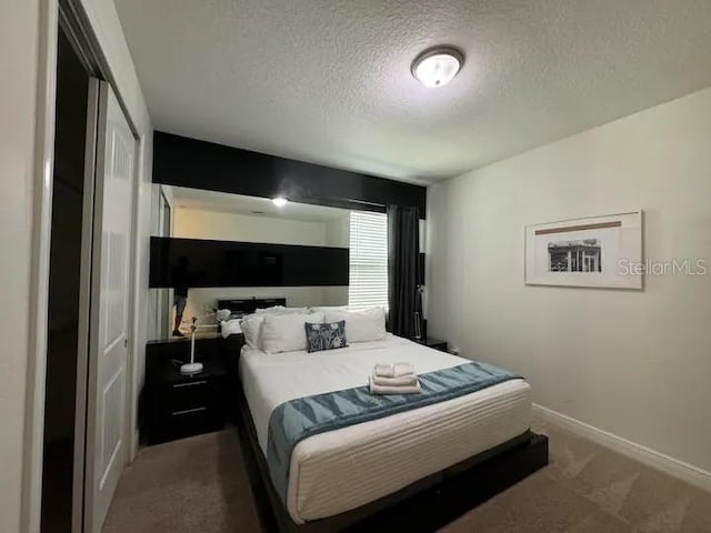 bedroom with baseboards, carpet floors, a textured ceiling, and a closet