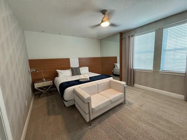 bedroom with baseboards, a textured ceiling, ceiling fan, and light colored carpet