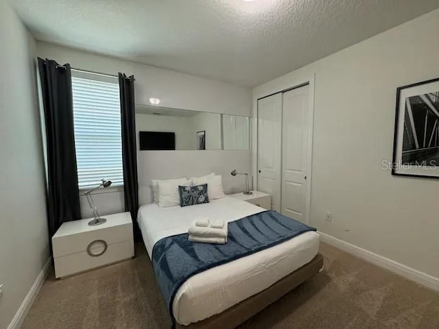 carpeted bedroom featuring a closet, a textured ceiling, and baseboards