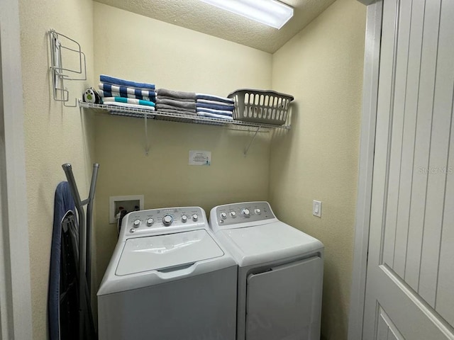 clothes washing area with washer and dryer, laundry area, and a textured ceiling