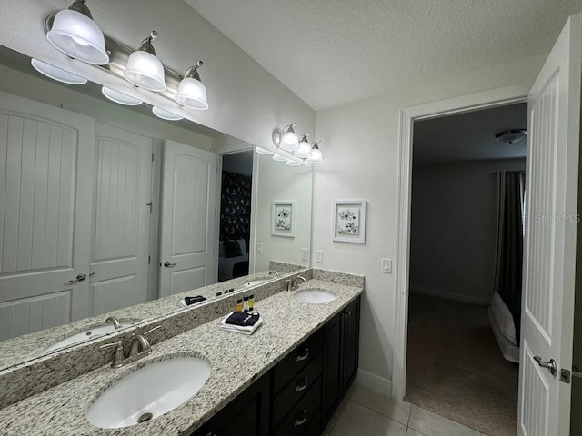 bathroom featuring tile patterned floors, double vanity, a sink, and a textured ceiling