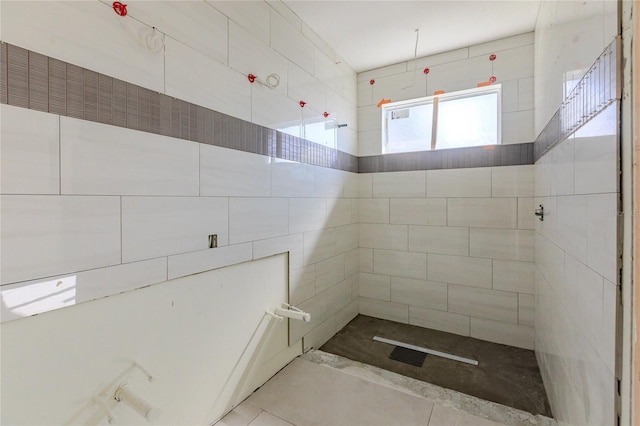 bathroom with a tile shower and tile patterned floors