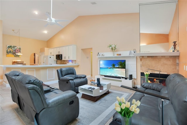 living room with ceiling fan, light tile patterned flooring, a fireplace, and high vaulted ceiling