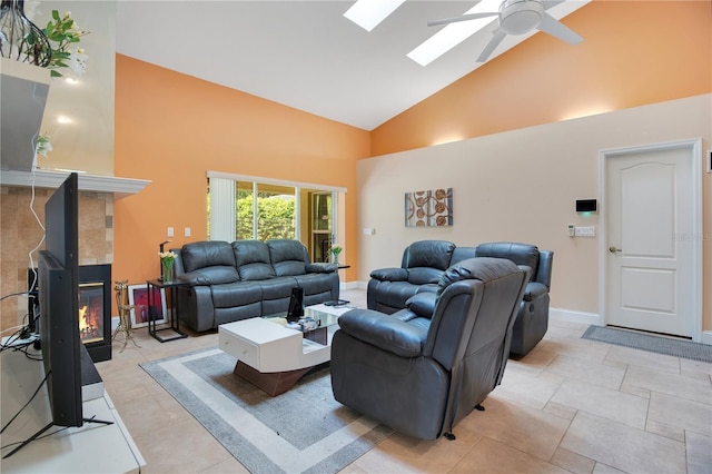 living room featuring high vaulted ceiling, a multi sided fireplace, a skylight, light tile patterned floors, and ceiling fan