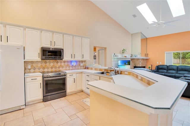 kitchen with ceiling fan, a skylight, sink, kitchen peninsula, and stainless steel appliances