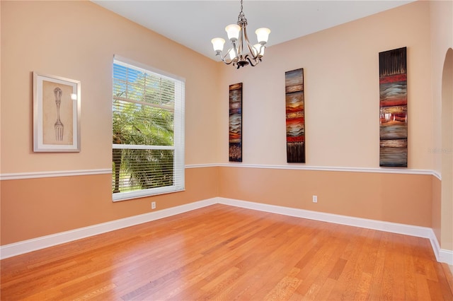 spare room featuring hardwood / wood-style floors and a notable chandelier