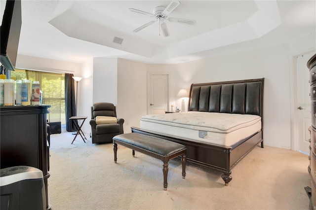 bedroom featuring a raised ceiling and light carpet