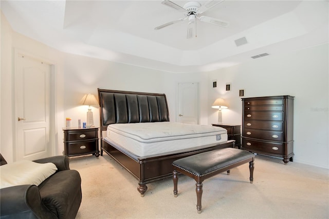 carpeted bedroom featuring a tray ceiling and ceiling fan