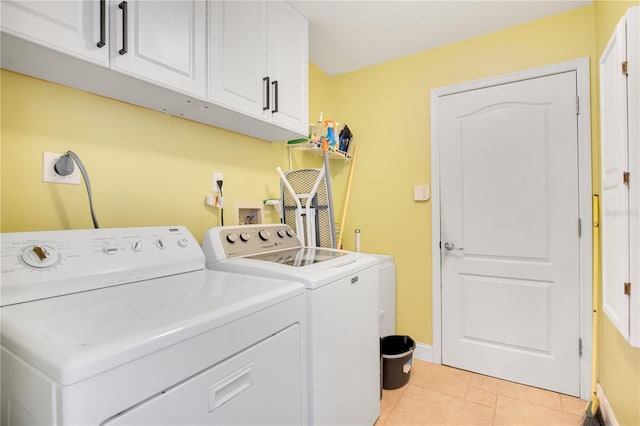 laundry area featuring cabinets, light tile patterned floors, and washing machine and dryer