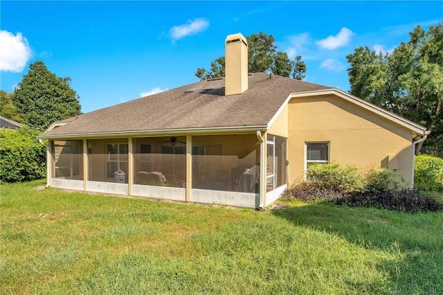 rear view of property featuring a sunroom and a yard