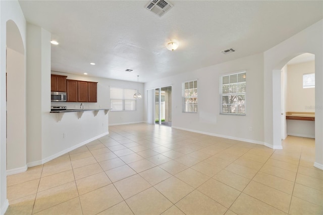 unfurnished living room featuring light tile patterned flooring and a wealth of natural light