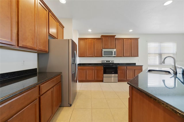 kitchen featuring dark stone counters, light tile patterned flooring, sink, and stainless steel appliances