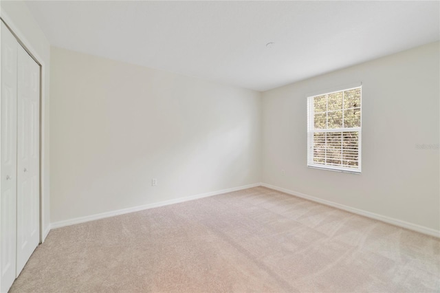 unfurnished bedroom with light carpet and a closet