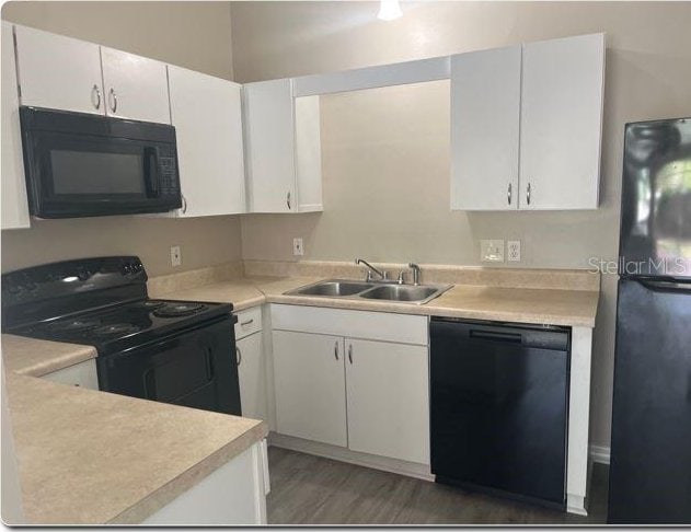 kitchen with black appliances, white cabinetry, dark wood-type flooring, and sink