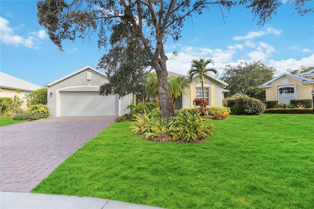 single story home featuring a front yard, decorative driveway, stucco siding, and an attached garage
