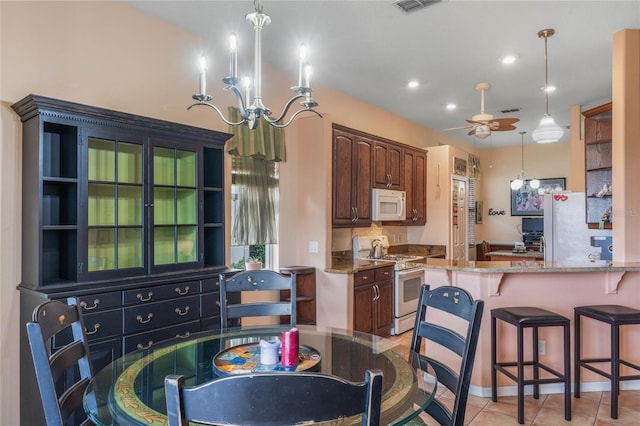 2366 Prairie Dunes, Clermont, FL 34711 - kitchen featuring light stone countertops, decorative light fixtures, white appliances, ceiling fan with notable chandelier, and a kitchen breakfast bar