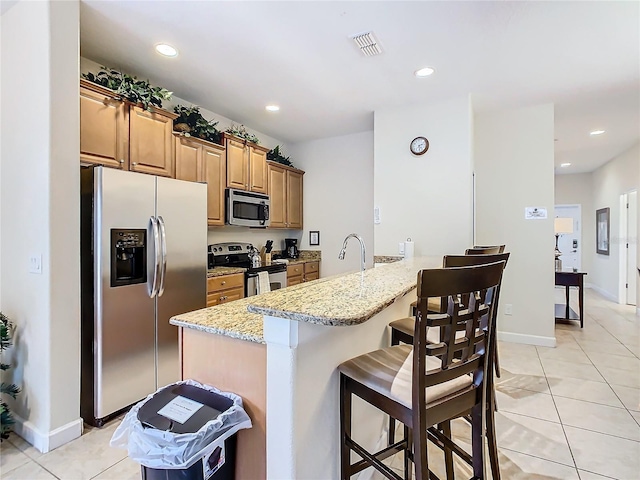 8967 California Palm Rd, Kissimmee, FL 34747 - kitchen with visible vents, light tile patterned floors, a kitchen bar, a peninsula, and stainless steel appliances