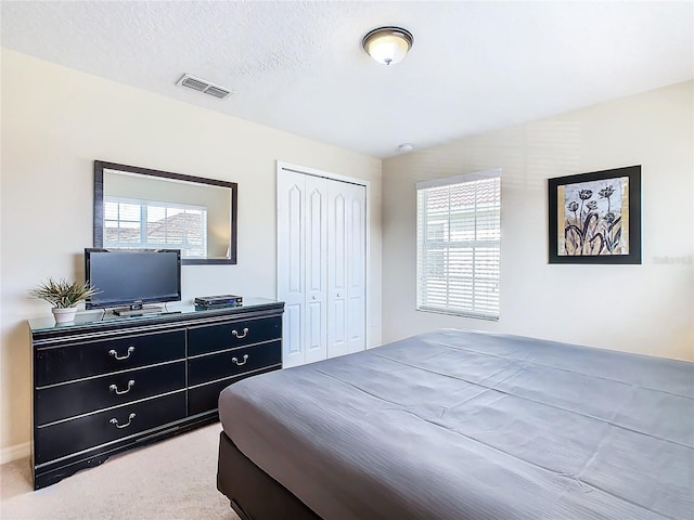 bedroom with a textured ceiling, a closet, carpet flooring, and multiple windows