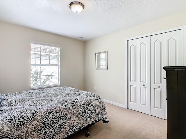 carpeted bedroom featuring a textured ceiling and a closet