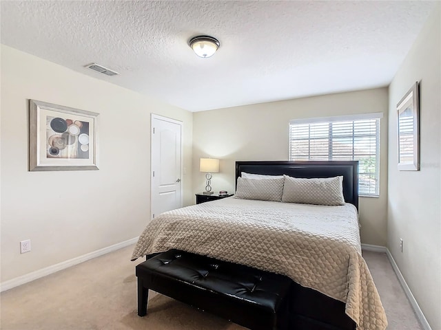 bedroom featuring a textured ceiling and light carpet