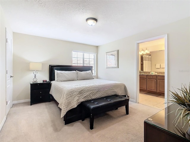 carpeted bedroom featuring a textured ceiling, connected bathroom, and a notable chandelier