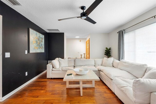 living room featuring ceiling fan, hardwood / wood-style flooring, and a textured ceiling