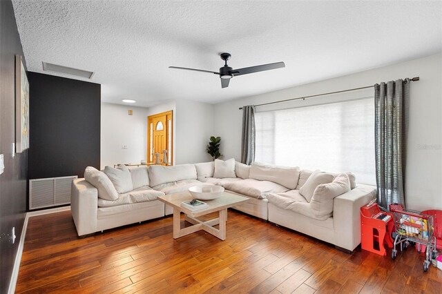 living room featuring ceiling fan, dark hardwood / wood-style floors, and a textured ceiling