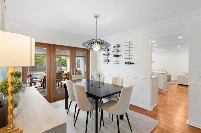 dining area featuring a textured ceiling, light wood-type flooring, and crown molding