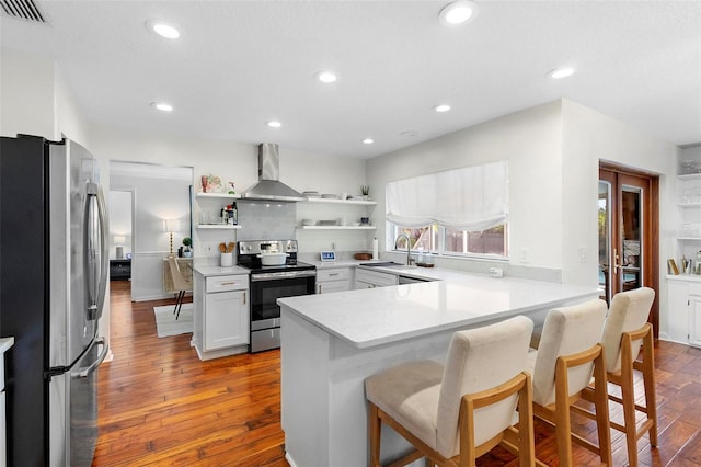 115 Marcy Blvd, Longwood, FL 32750 - kitchen with visible vents, a peninsula, wall chimney exhaust hood, appliances with stainless steel finishes, and open shelves