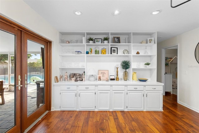 bar with french doors, white cabinets, and dark wood-type flooring