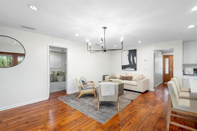 living room featuring a textured ceiling, hardwood / wood-style floors, and a notable chandelier