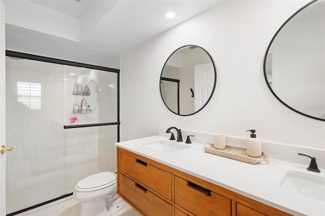 bathroom with vanity, toilet, and a shower with door