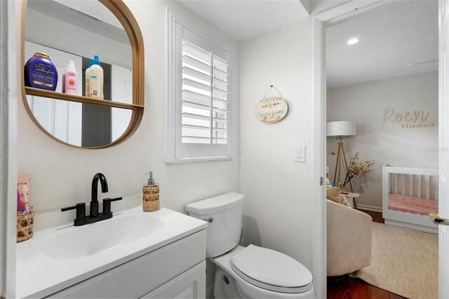 bathroom with wood-type flooring, vanity, and toilet