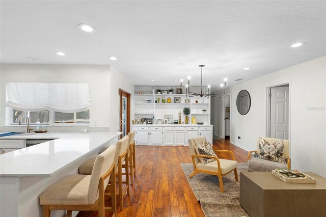 interior space with a textured ceiling, wood-type flooring, sink, and a notable chandelier