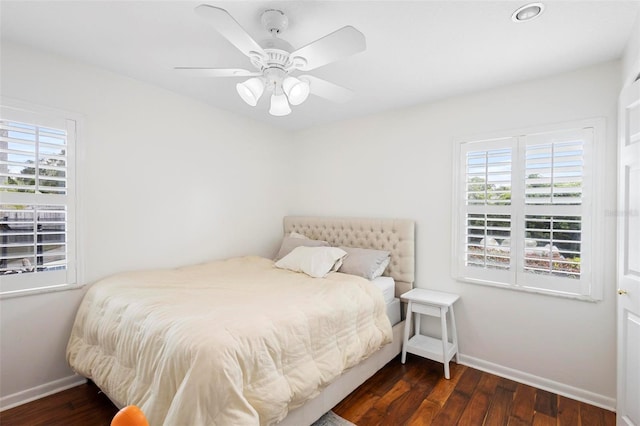 bedroom featuring ceiling fan, multiple windows, and dark wood-type flooring