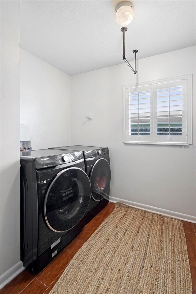 clothes washing area featuring dark wood-type flooring and washer and dryer