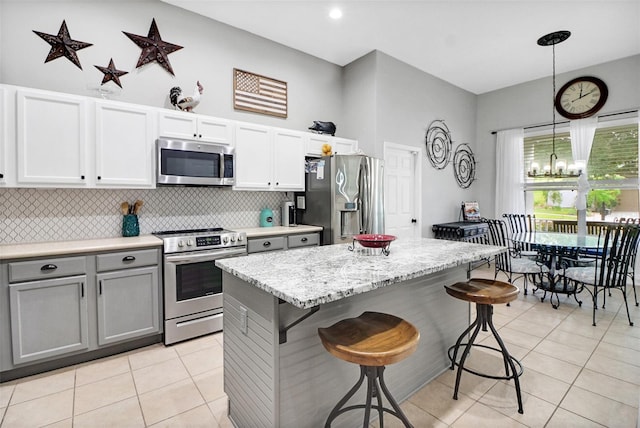 kitchen with white cabinets, pendant lighting, gray cabinets, light tile patterned flooring, and appliances with stainless steel finishes