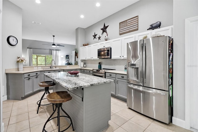 kitchen with a kitchen breakfast bar, sink, ceiling fan, kitchen peninsula, and stainless steel appliances