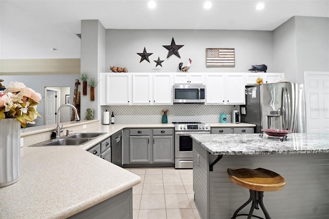 kitchen with kitchen peninsula, a kitchen breakfast bar, stainless steel appliances, sink, and white cabinetry