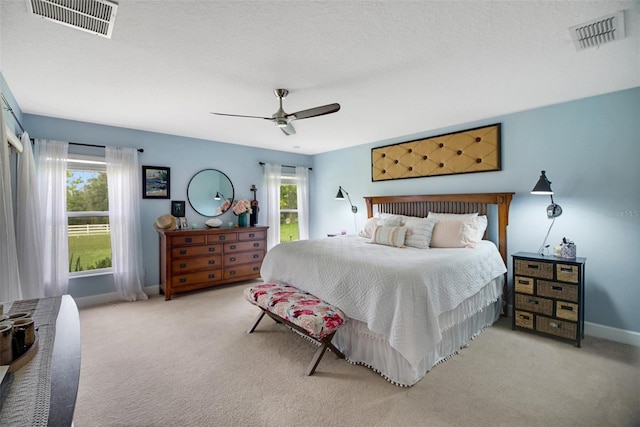 carpeted bedroom with multiple windows, ceiling fan, and a textured ceiling