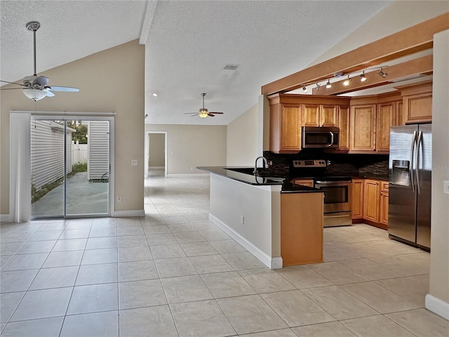 kitchen featuring light tile patterned floors, kitchen peninsula, rail lighting, appliances with stainless steel finishes, and decorative backsplash