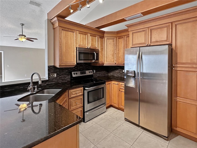 kitchen featuring a textured ceiling, sink, vaulted ceiling, appliances with stainless steel finishes, and dark stone countertops