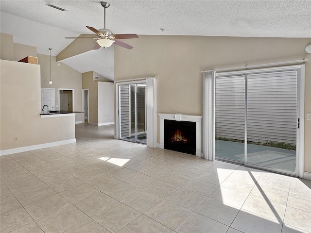 unfurnished living room with a textured ceiling, light tile patterned floors, ceiling fan, and high vaulted ceiling