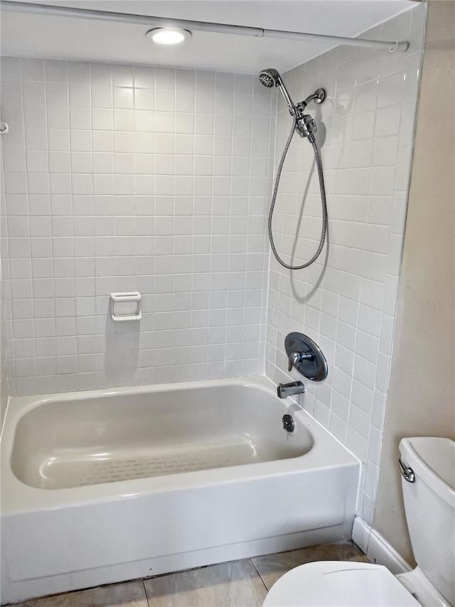 bathroom with tiled shower / bath combo and toilet