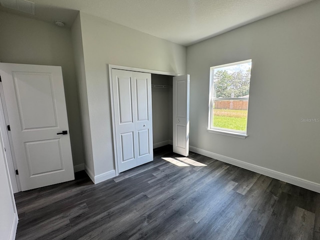 unfurnished bedroom featuring a textured ceiling, a closet, and dark hardwood / wood-style floors