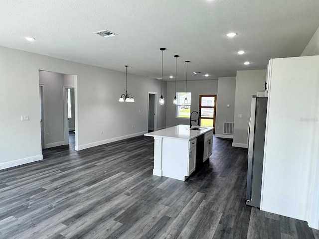 kitchen with hanging light fixtures, an island with sink, stainless steel refrigerator, and white cabinetry