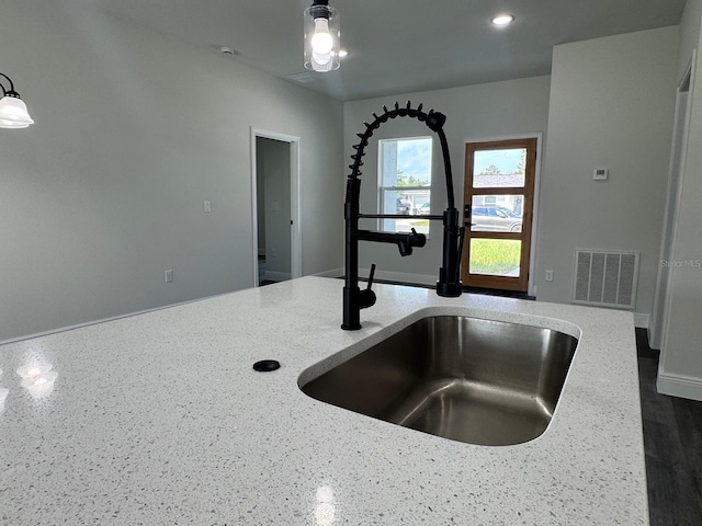 interior details featuring pendant lighting, light stone countertops, dark wood-type flooring, and sink